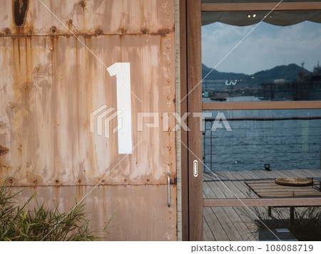 The sea and natural scenery reflected in the rusted iron doors and windows of the warehouse 108088719