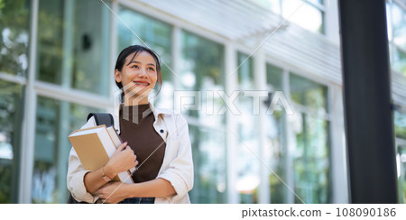 Beautiful young woman Asian with backpack and book. University student carrying lots of books in college campus. College and University life concept 108090186
