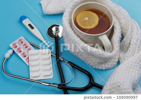 Healthcare, medicine, flu and treatment concept. Tea, stethoscope with thermometer and pills. 108090997