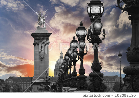 Lamp posts on Alexander III Bridge against the background of a beautiful sky at sunset. Paris, France. This arch bridge is one of the most beautiful river crossings in the world Lamp posts on Alexander III Bridge against the background of a beautiful sky at sunset. Paris, France. This arch bridge is one of the most beautiful river crossings in the world 108092150