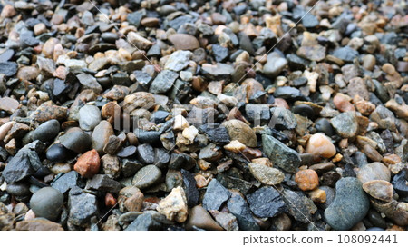 wet gravel close-up blurred along the edge of the picture, gray crushed rock mineral interspersed with various rocks, pebble texture wallpaper full frame, crushed stone as a building material 108092441