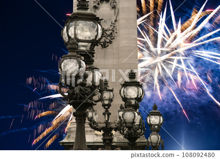 Celebratory colorful fireworks over the Lamp posts on Alexander III Bridge. Paris, France. This arch bridge is one of the most beautiful river crossings in the world 108092480