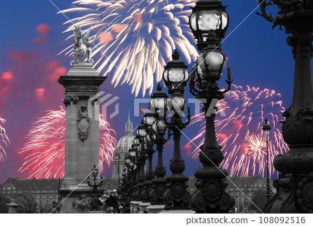 Celebratory colorful fireworks over the Lamp posts on Alexander III Bridge. Paris, France. This arch bridge is one of the most beautiful river crossings in the world 108092516
