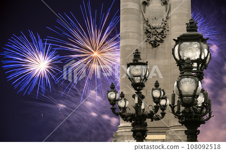 Celebratory colorful fireworks over the Lamp posts on Alexander III Bridge. Paris, France. This arch bridge is one of the most beautiful river crossings in the world 108092518