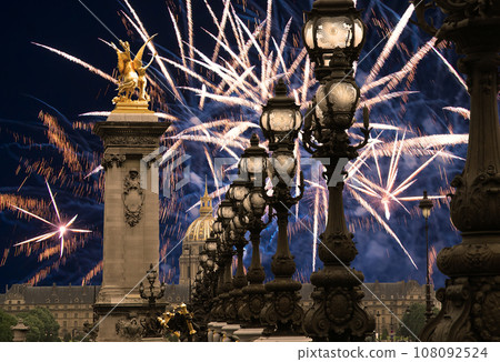 Celebratory colorful fireworks over the Lamp posts on Alexander III Bridge. Paris, France. This arch bridge is one of the most beautiful river crossings in the world Celebratory colorful fireworks over the Lamp posts on Alexander III Bridge. Paris, France. This arch bridge is one of the most beautiful river crossings in the world 108092524