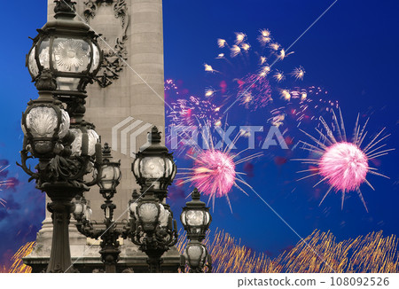 Celebratory colorful fireworks over the Lamp posts on Alexander III Bridge. Paris, France. This arch bridge is one of the most beautiful river crossings in the world Celebratory colorful fireworks over the Lamp posts on Alexander III Bridge. Paris, France. This arch bridge is one of the most beautiful river crossings in the world 108092526