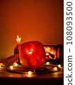 Halloween pumpkin with a comically carved face sits on a table, atmosphere is enhanced by warm 108093500