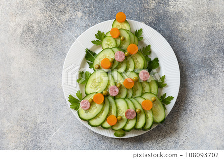 Christmas tree from a salad olivier on a gray stone background. Christmas appetizer. View from above. Christmas tree from a salad olivier on a gray stone background. Christmas appetizer. View from above. 108093702