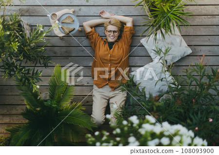 Top view of woman relaxing in the garden, eating sandwich. Mother having moment to herself while her child is sleeping, eating light lunch in peace. Top view of woman relaxing in the garden, eating sandwich. Mother having moment to herself while her child is sleeping, eating light lunch in peace. 108093900
