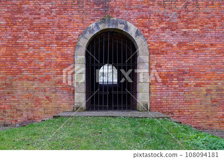 A passage closed by a lattice in an old brick fortress wall. Antique brickwork. 108094181