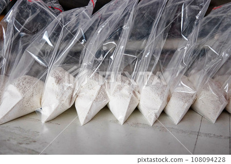 A large number of transparent sachets filled with white powder. White powder packaged in small sachets. 108094228