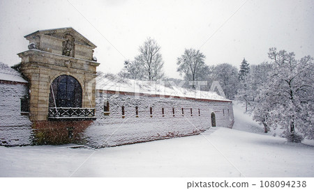 Fragment of an old fortress wall in the Polish city of Zamosc during a snowfall. An old Eastern European fortification. Architectural monument. Snowfall. Fragment of an old fortress wall in the Polish city of Zamosc during a snowfall. An old Eastern European fortification. Architectural monument. Snowfall. 108094238