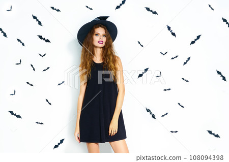 happy young woman in black witch halloween costume on party over white background with bats. happy young woman in black witch halloween costume on party over white background with bats. 108094398