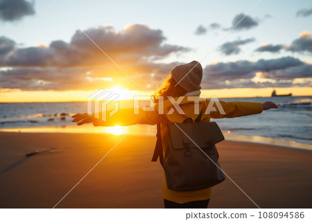 Tourist in yellow jacket enjoying sea landscape at sunset. Lifestyle, travel, nature, active life. Tourist in yellow jacket enjoying sea landscape at sunset. Lifestyle, travel, nature, active life. 108094586