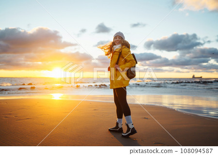 Tourist in yellow jacket enjoying sea landscape at sunset. Lifestyle, travel, nature, active life. Tourist in yellow jacket enjoying sea landscape at sunset. Lifestyle, travel, nature, active life. 108094587
