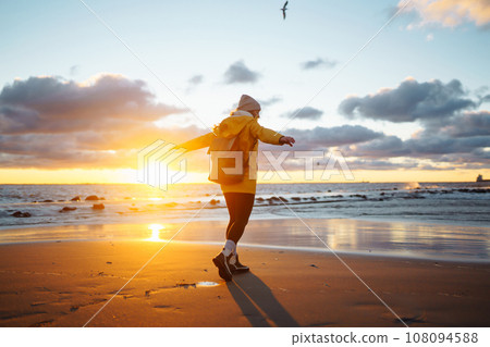 Tourist in yellow jacket enjoying sea landscape at sunset. Lifestyle, travel, nature, active life. 108094588