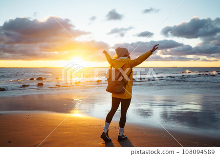 Tourist in yellow jacket enjoying sea landscape at sunset. Lifestyle, travel, nature, active life. Tourist in yellow jacket enjoying sea landscape at sunset. Lifestyle, travel, nature, active life. 108094589