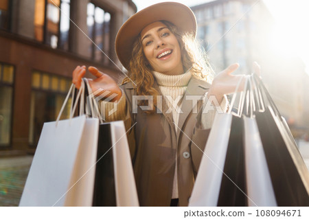 Smiling woman after shopping on city street. Purchases, sale concept. Online shopping concept. 108094671