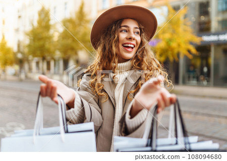 Smiling woman after shopping on city street. Purchases, sale concept. Online shopping concept. 108094680