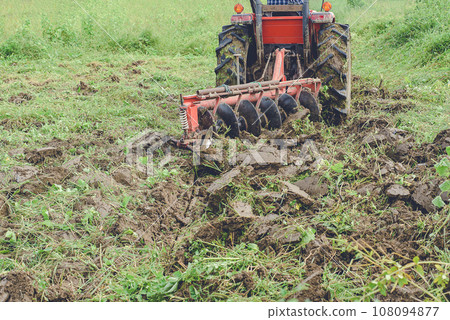 Tractor Tilling the Soil with Vibrant Green Grass Background 108094877