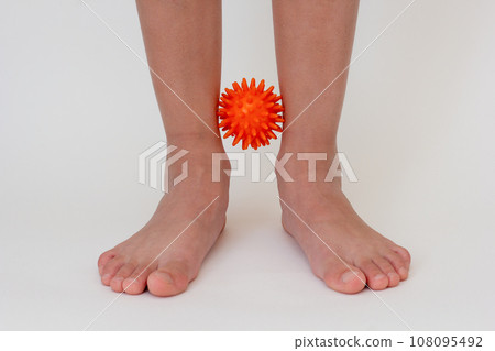 Cropped child legs doing exercises with spiky needle ball  108095492