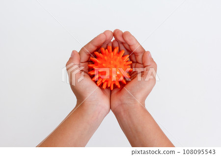 Child hands holding orange spiky ball for massage 108095543