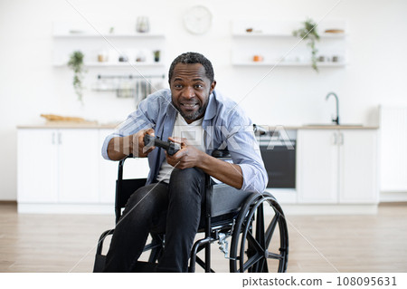 african male gamer with mobility impairment with input devices 108095631