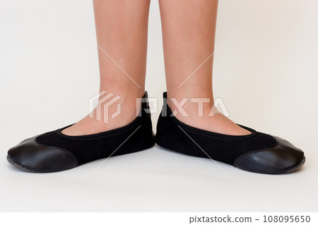 Cropped child legs in black leather ballet shoes Cropped child legs in black leather ballet shoes 108095650