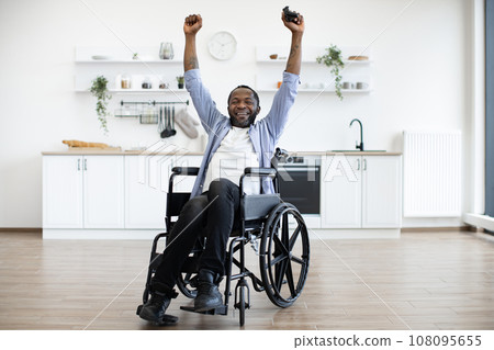 African person in wheelchair raising hands with joystick African person in wheelchair raising hands with joystick 108095655