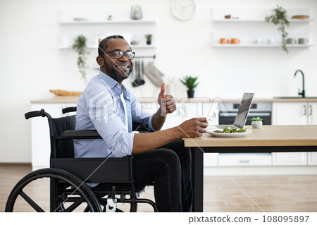 Manager with disability enjoying food in home workplace 108095897