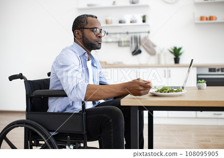 Man with disability having lunch at distance work indoors 108095905