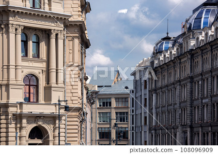 Facade of a monumental building with architectural elements of stucco and columns, street of the old city with different buildings. Facade of a monumental building with architectural elements of stucco and columns, street of the old city with different buildings. 108096909