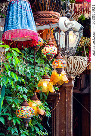 decorated terrace of the cafe, facade is decorated with different chandeliers and green leaves, closeup decor, nobody. 108096921