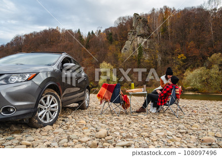 couple having picnic at autumn mountain river couple having picnic at autumn mountain river 108097496