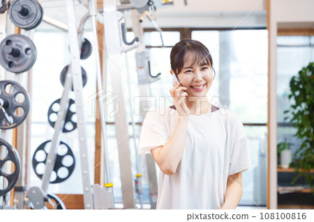 Woman talking on smartphone at gym Woman talking on smartphone at gym 108100816