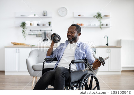 Person with disability raising dumbbells in kitchen interior Person with disability raising dumbbells in kitchen interior 108100948