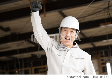Worker working as a site supervisor at a construction site, fist pumping while looking at the camera Worker working as a site supervisor at a construction site, fist pumping while looking at the camera 108101138