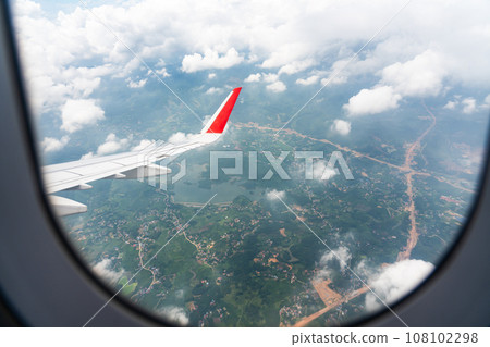 The wing of an airplane flying over Vietnam and the view below 108102298