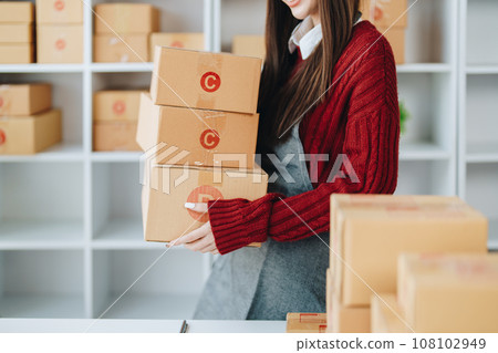 Asian female business owner handles delivery of orders to customers. 108102949