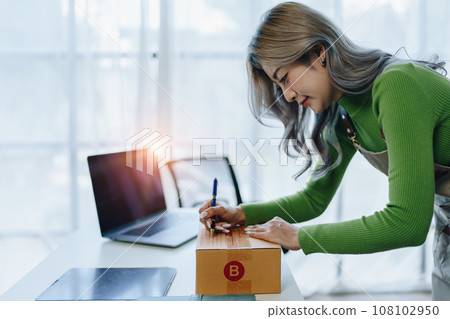 Starting small business entrepreneur of independent Asian female online seller packing products to send to customers and SME delivery concept. Starting small business entrepreneur of independent Asian female online seller packing products to send to customers and SME delivery concept. 108102950