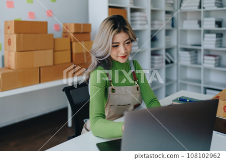 Starting small business entrepreneur of independent young Asian woman online seller is using computer and taking orders to pack products for delivery to customers. SME delivery concept. 108102962