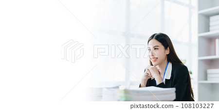 Portrait of a woman business owner showing a happy smiling face as he has successfully invested her business using computers and financial budget documents at work. Portrait of a woman business owner showing a happy smiling face as he has successfully invested her business using computers and financial budget documents at work. 108103227