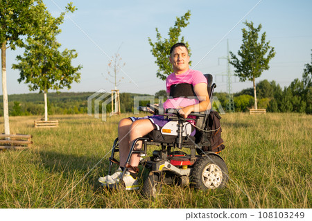 A man with disabilities in an electric wheelchair at the park. 108103249