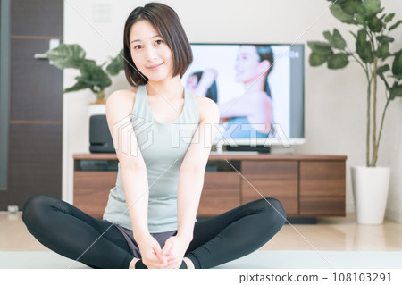 A young woman stretching in the living room 108103291