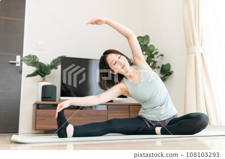 A young woman stretching in the living room 108103293