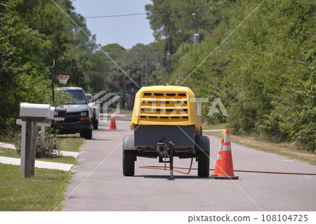 Yellow jackhammer machine with compressor trailer on road construction site Yellow jackhammer machine with compressor trailer on road construction site 108104725