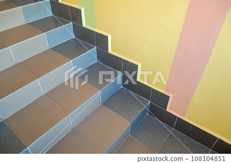 Wide staicase covered with ceramic tiles indoors in a house interior. Wide staicase covered with ceramic tiles indoors in a house interior. 108104851