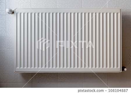 White metal heating radiator mounted on a wall in room interior. 108104887