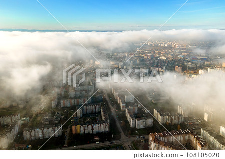 Top aerial view of fluffy white clouds over modern city with high rise buildings. 108105020