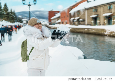Woman tourist Visiting in Otaru, happy Traveler in Sweater sightseeing Otaru canal with Snow in winter season. landmark and popular for attractions in Hokkaido, Japan. Travel and Vacation concept 108105076